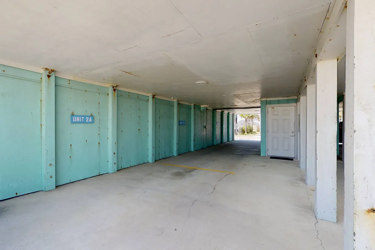 A practical interior utility area featuring blue unit doors, concrete flooring, and a white door, suggesting a laundry or storage area. The mood is functional, highlighting ease of access and hassle-free cleaning—ideal for dealing with sandy paws.