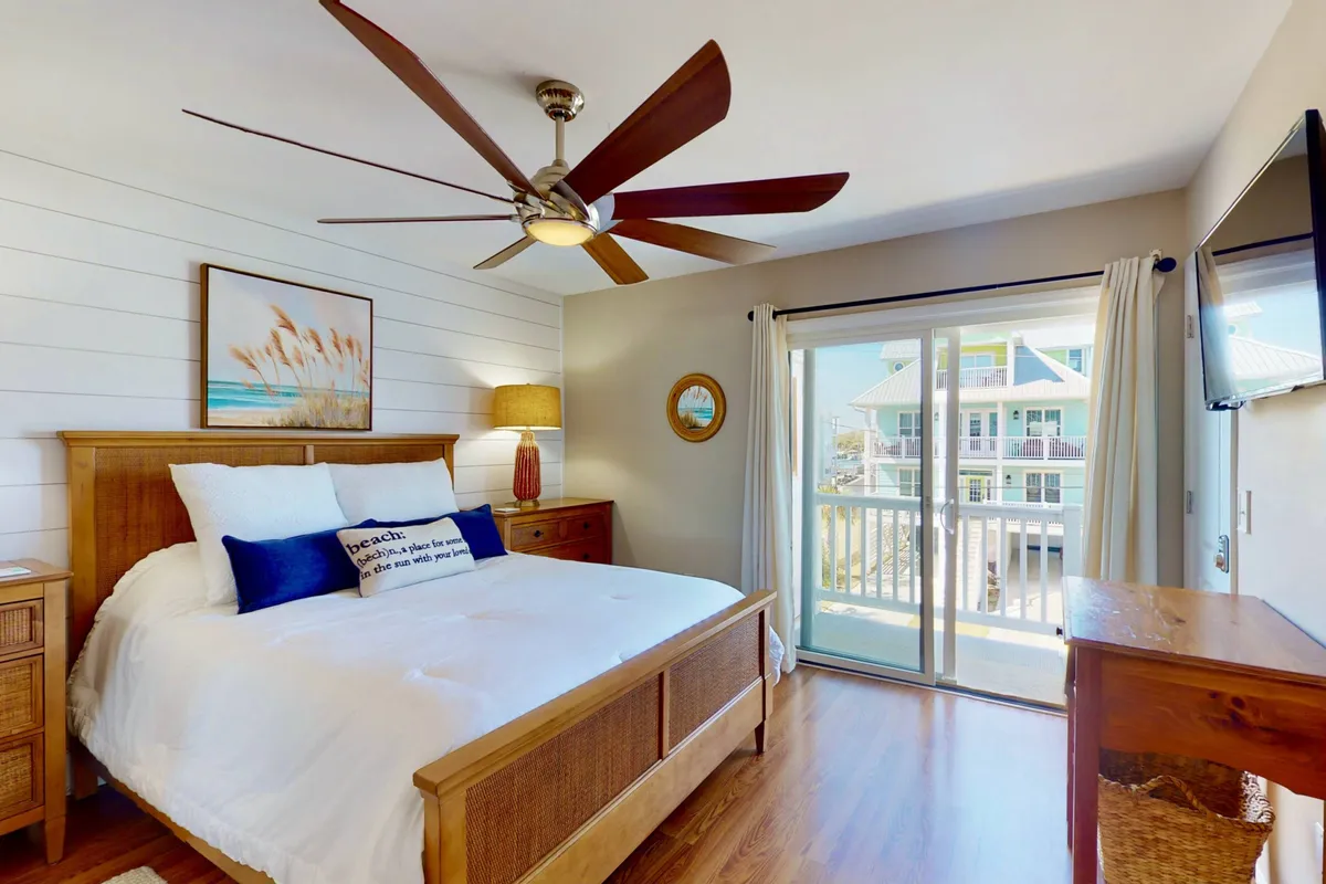 A tranquil bedroom with a plush bed, ceiling fan, soft lighting, and a window offering a gentle view outside. The bed is dressed with crisp linens, and tasteful artwork hangs above the headboard, creating a serene and inviting atmosphere ideal for deep relaxation and rejuvenation.