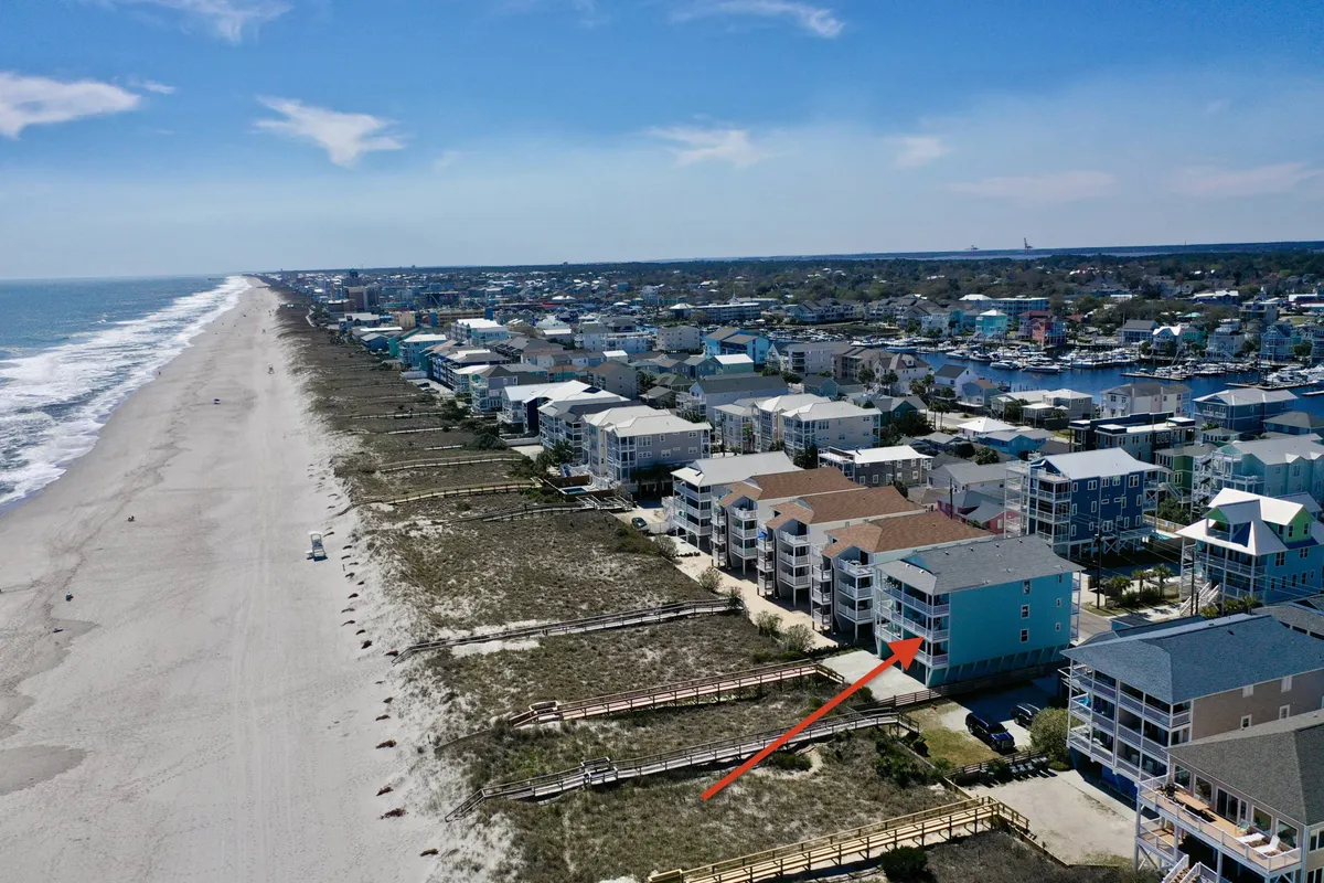 A vibrant coastal scene showcasing colorful beachfront buildings, sandy beach, and a prominent boardwalk. The image conveys the connection between the beach and the lively local community, with ample space for sunbathing, swimming, and walking along the shore.